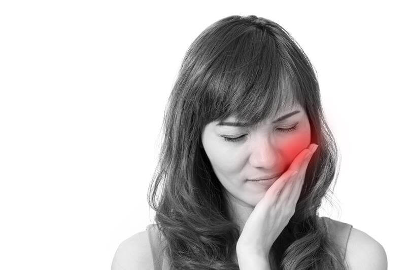 black and white photo of womans face with red cheek showing toothache