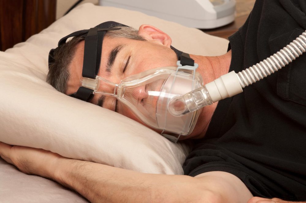 man sleeping with sleep apnea machine on